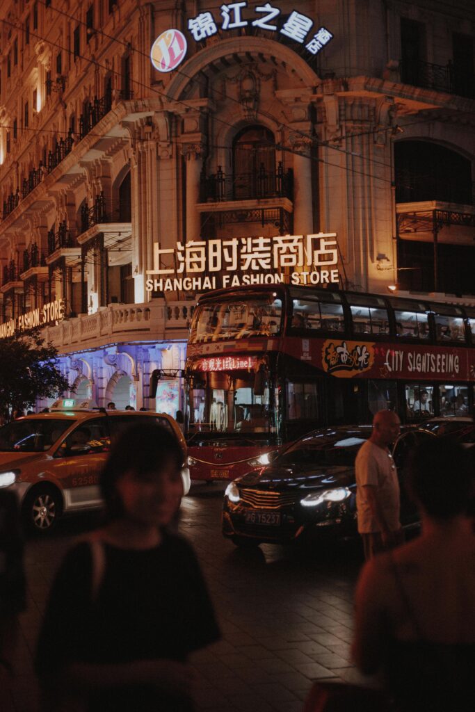 Explore the vibrant nightlife on a bustling street in Shanghai, China, featuring a city sightseeing bus and bright lights.