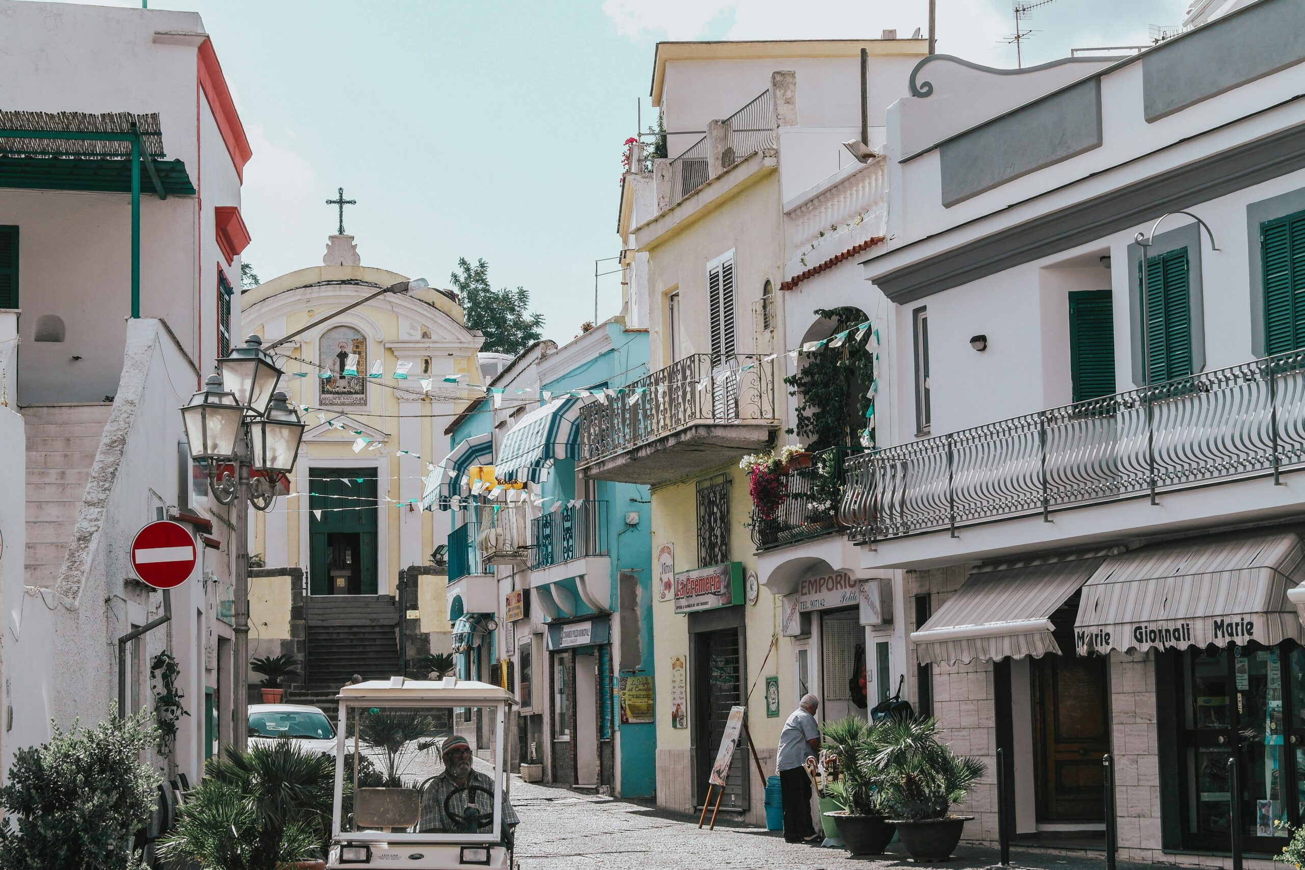 Quaint street view in Ischia, Italy showcasing colorful facades and local life.