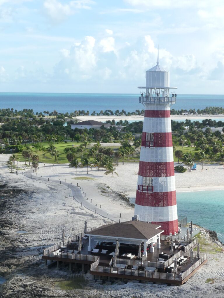 Travel A picturesque red and white lighthouse stands by a tropical shore, offering nautical charm and coastal views.