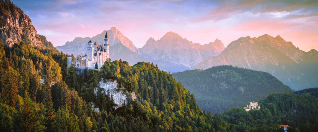 Travel Breathtaking view of Neuschwanstein Castle with Alps in the background during sunset.